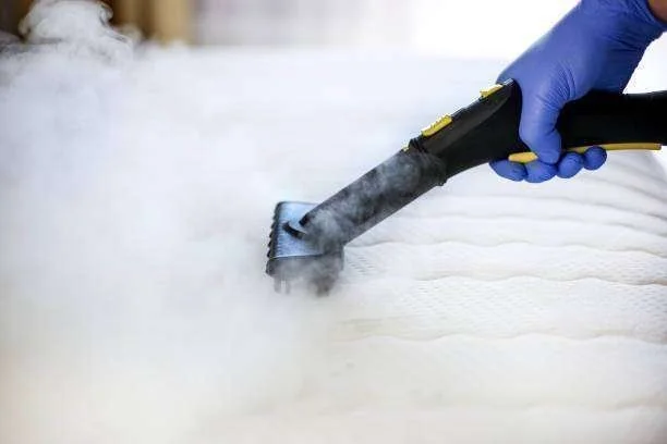 Higienização de colchão branco com vaporizador, operado por mão com luva azul